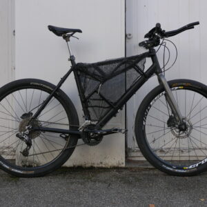 vue de droite d'un vélo de voyage noir avec filet de pêche dans le triangle avant / "Vélo de bikepacking ninja tout-terrain noir"