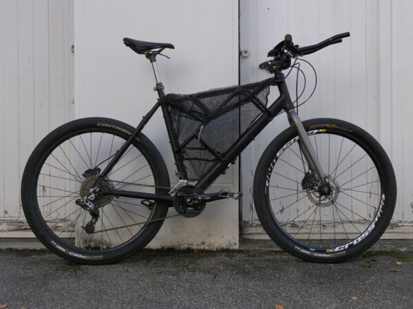 vue de droite d'un vélo de voyage noir avec filet de pêche dans le triangle avant / "Vélo de bikepacking ninja tout-terrain noir"